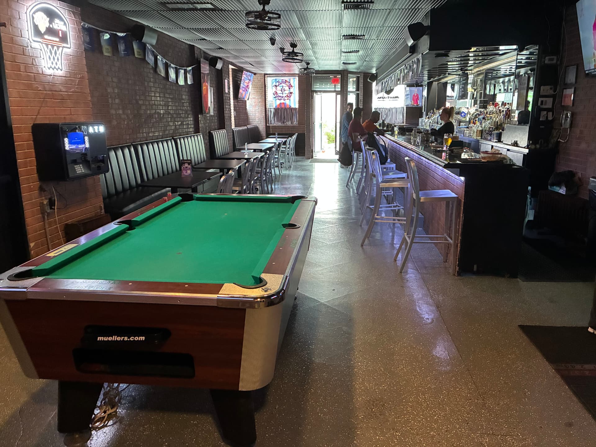 The pool table, seating, and long bar inside The Celly
