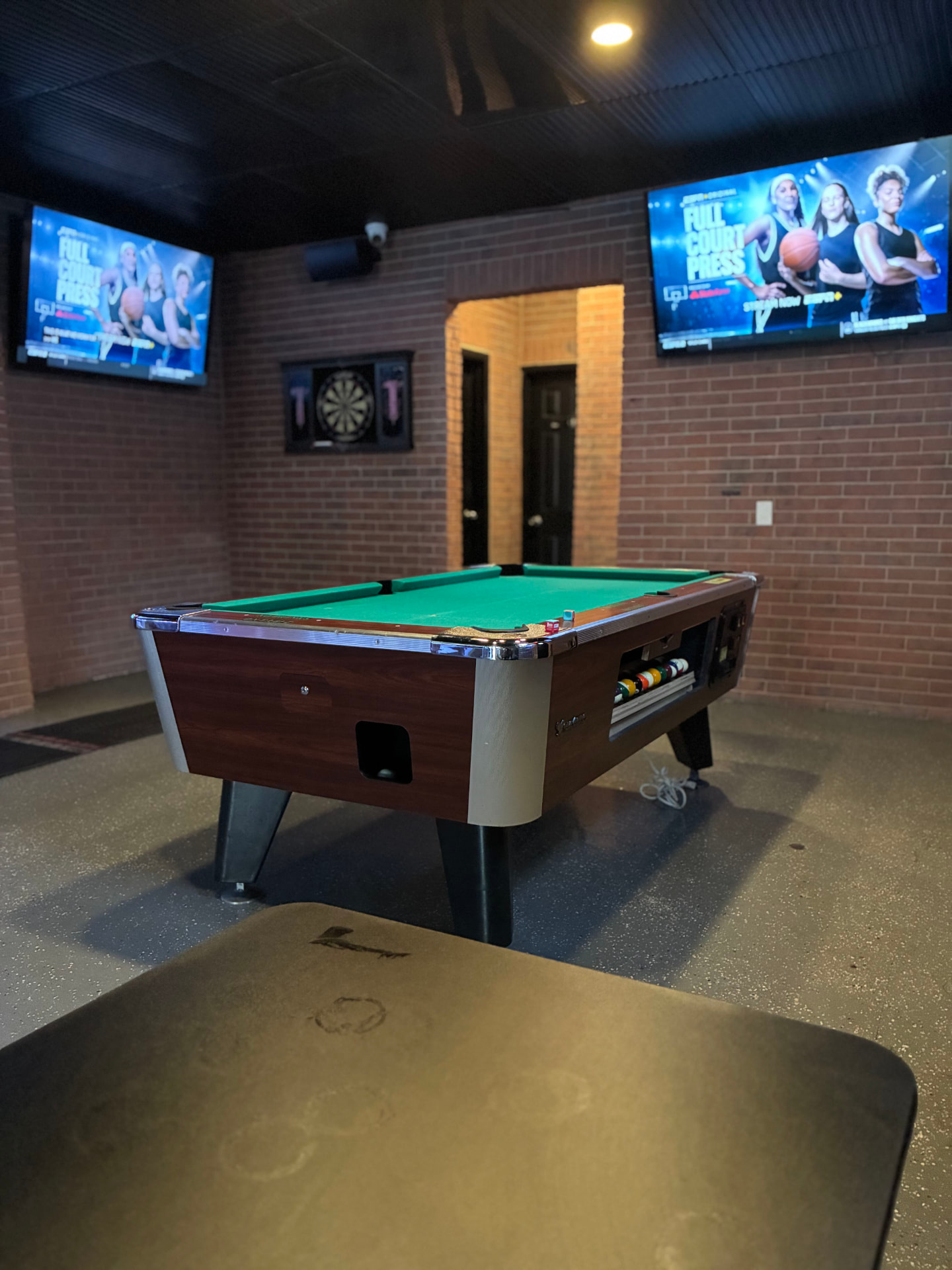Pool table and brick walls lined with TVs