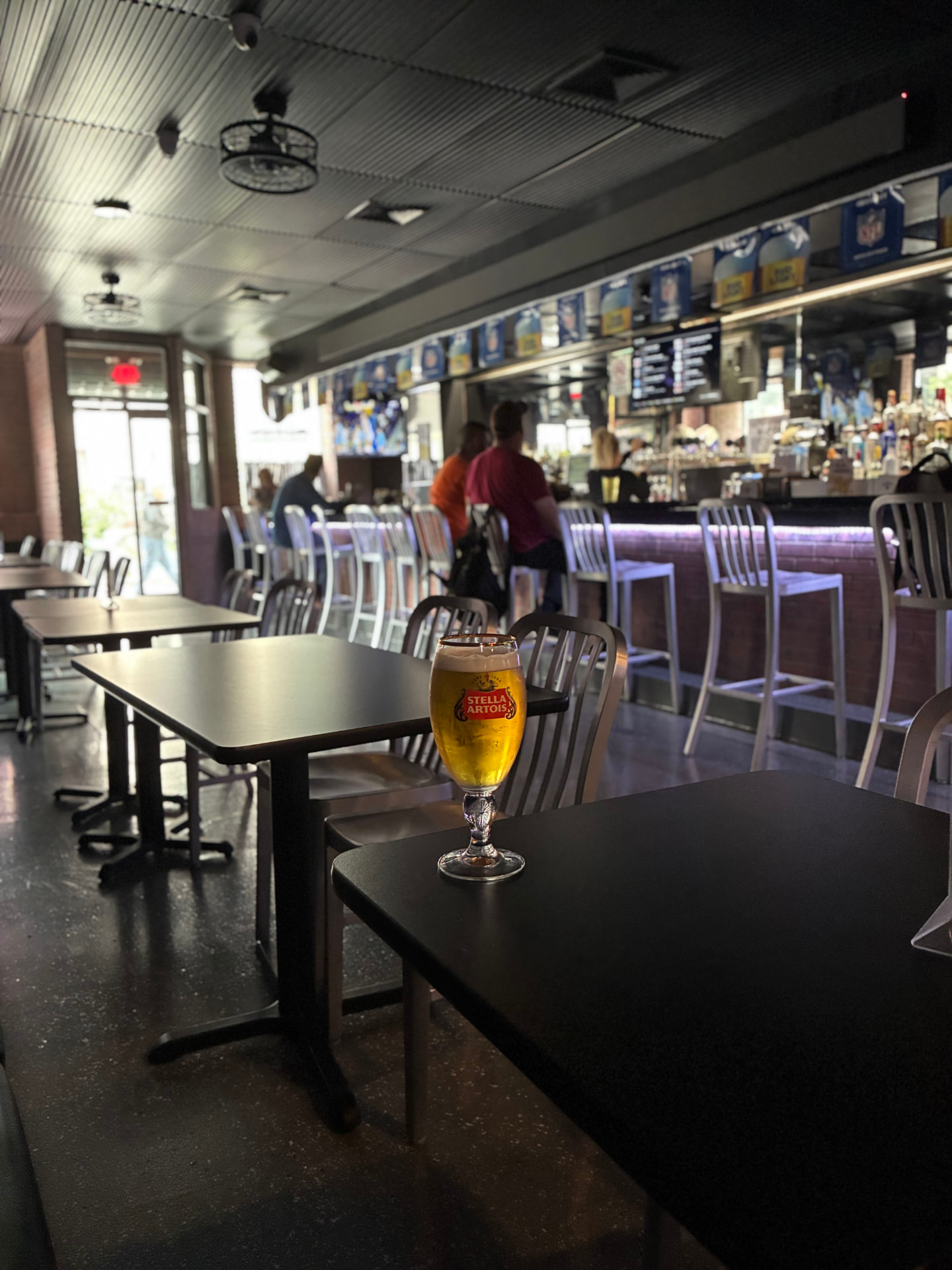 A cold pint with the long bar behind it